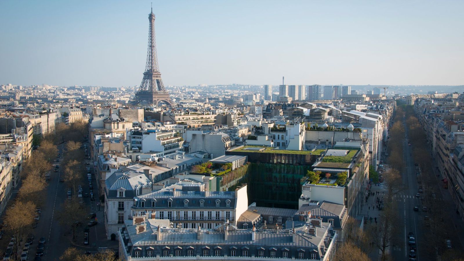 View over Haussmann rooftops and tree-lined avenues of a prestigious Paris district with the Eiffel Tower