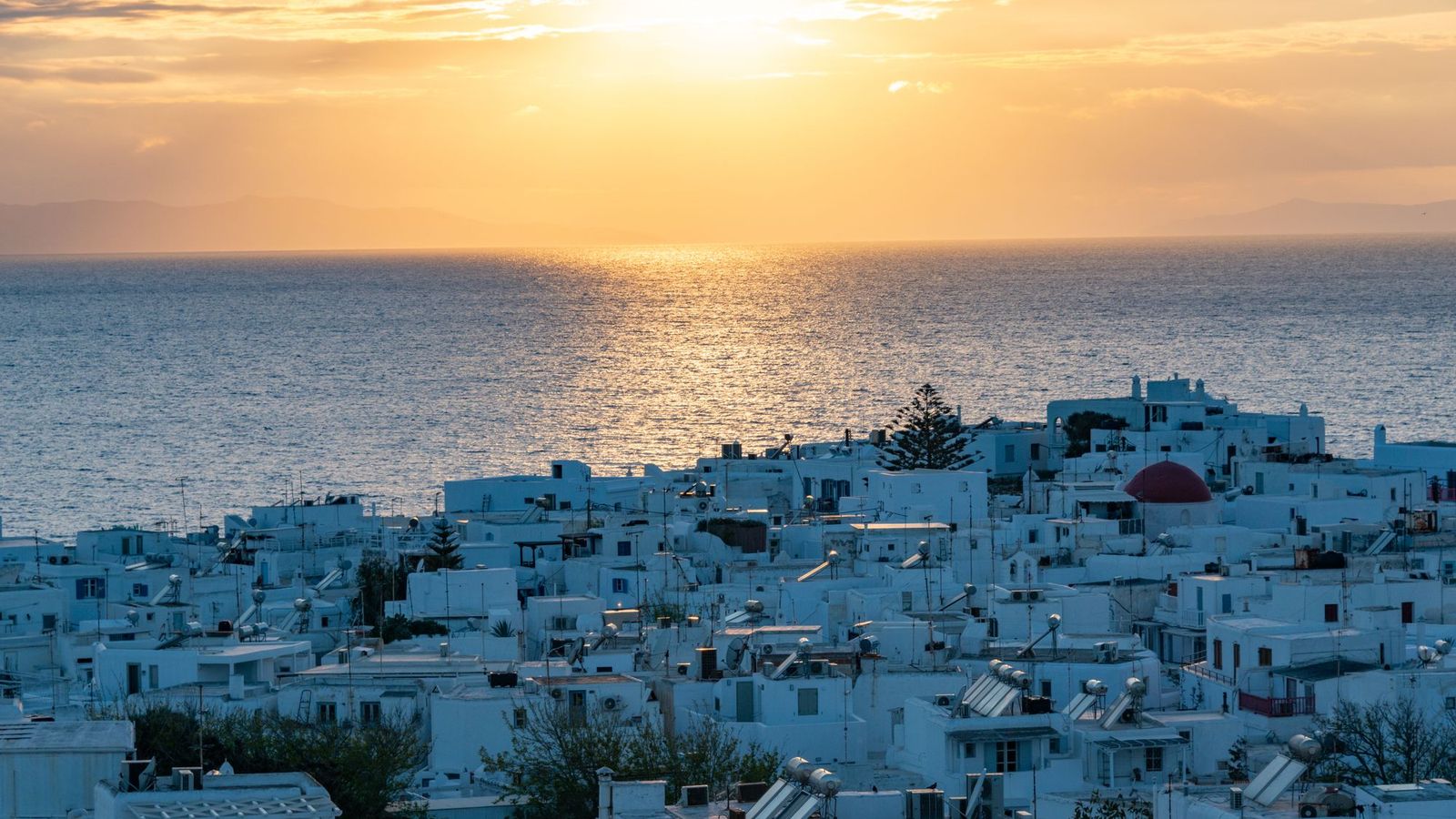 Whitewashed Cycladic houses of Mykonos town overlooking the Aegean Sea at sunset